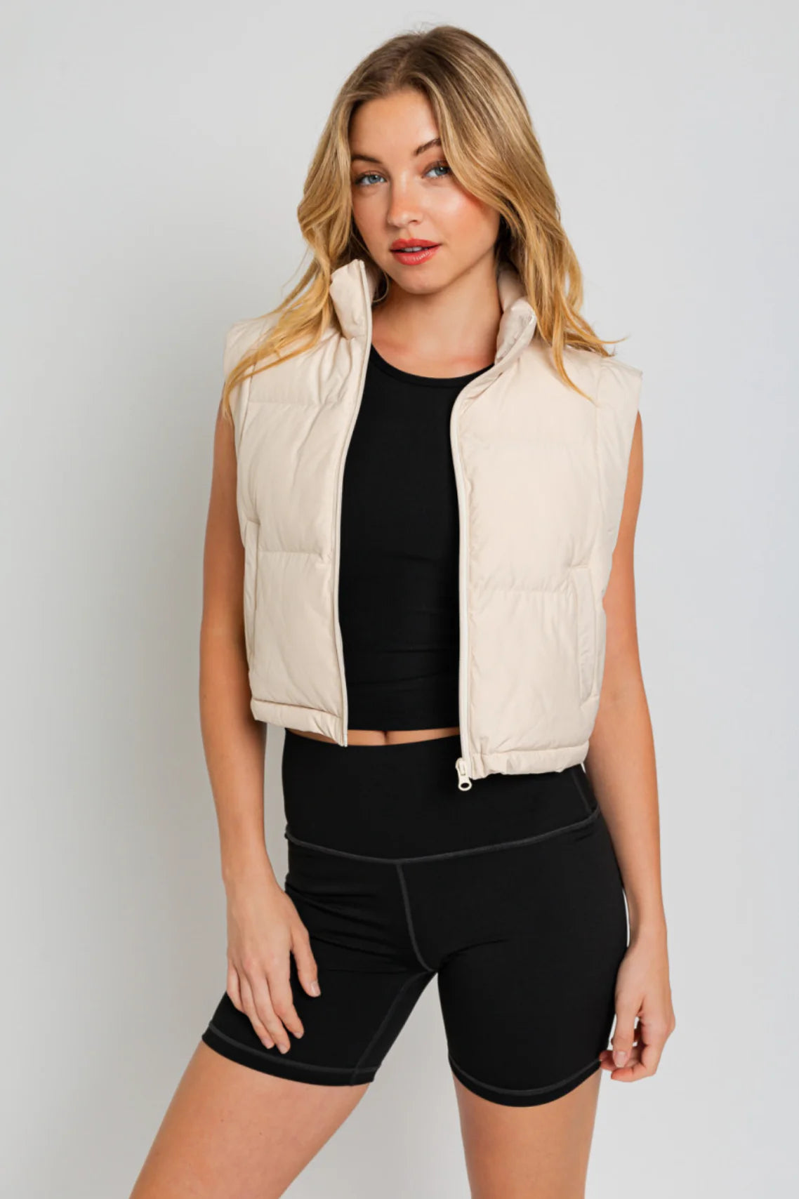 Beige puffer vest with black biker shorts.