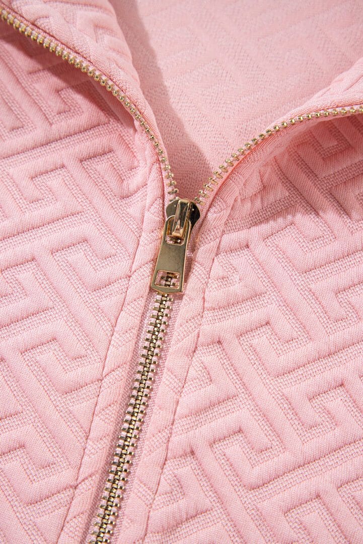 A close up of the zipper on a pink jacket