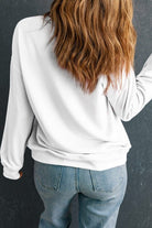 A woman with long hair is wearing jeans and white sweatshirt.