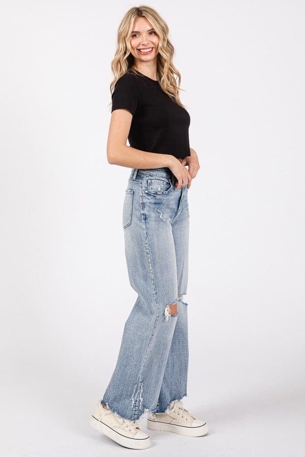 A woman in black shirt and jeans standing on top of a ledge.