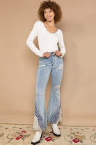 Woman in white top and bell-bottom jeans.