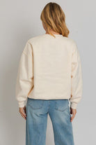 Woman in cream sweatshirt and jeans.