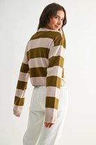 Model wearing light taupe and olive bold stripe crewneck sweater with wide horizontal stripes.
