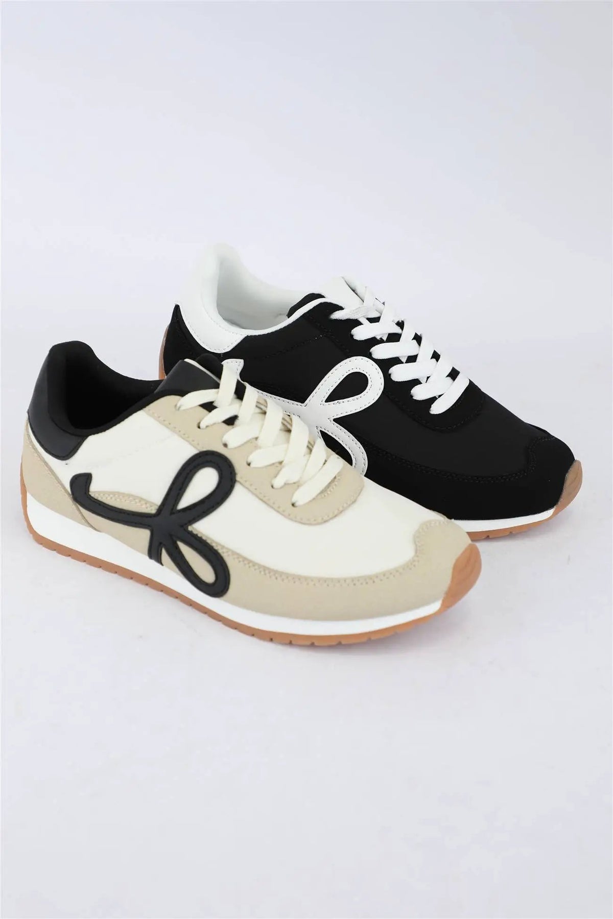 Retro low-top sneakers in cream taupe and black with gum soles. Sporty lace-up casual shoes featuring distinct contrasting side accents for everyday wear.