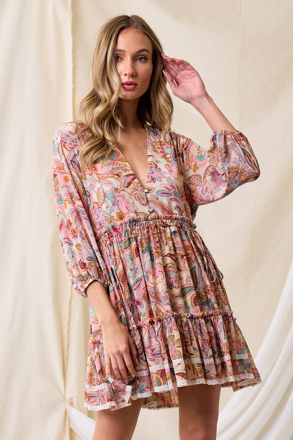 Model wearing The Western Paisley Tier Dress in pink paisley print with tiered skirt and lace trim.