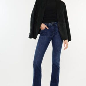 A woman wearing jeans and black sweater standing on one leg.