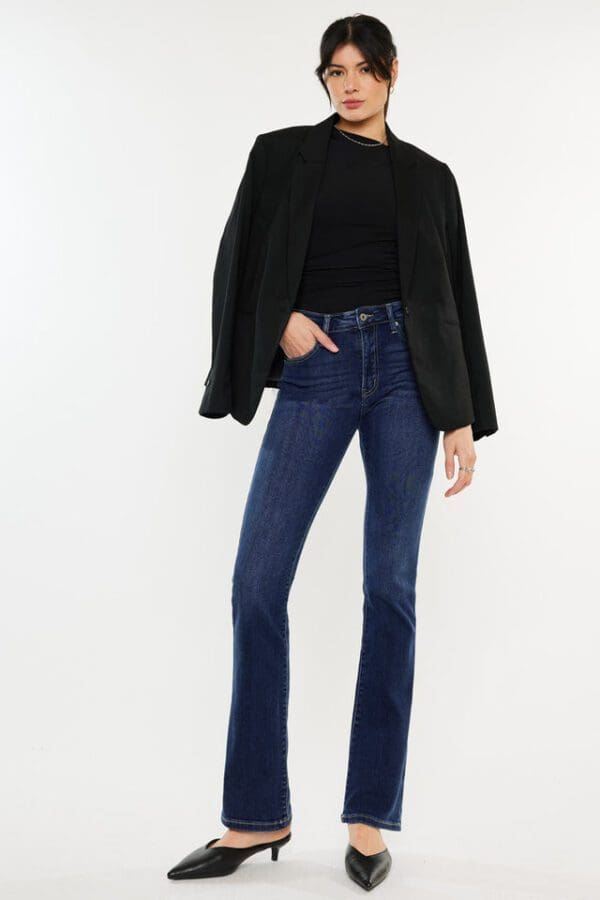 A woman wearing jeans and black sweater standing on one leg.