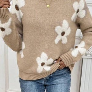 A woman wearing jeans and a sweater with white flowers.