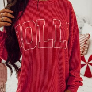 A person standing in front of a wall wearing a red sweater.