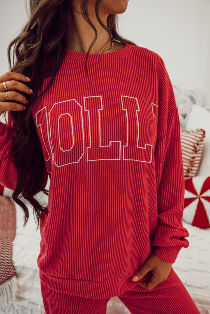 A person standing in front of a wall wearing a red sweater.