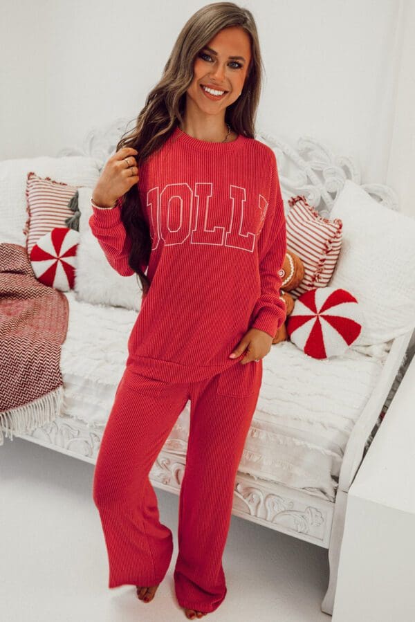 A woman in red pajamas standing next to a white couch.