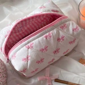 A pink and white quilted bag sitting on top of a table.