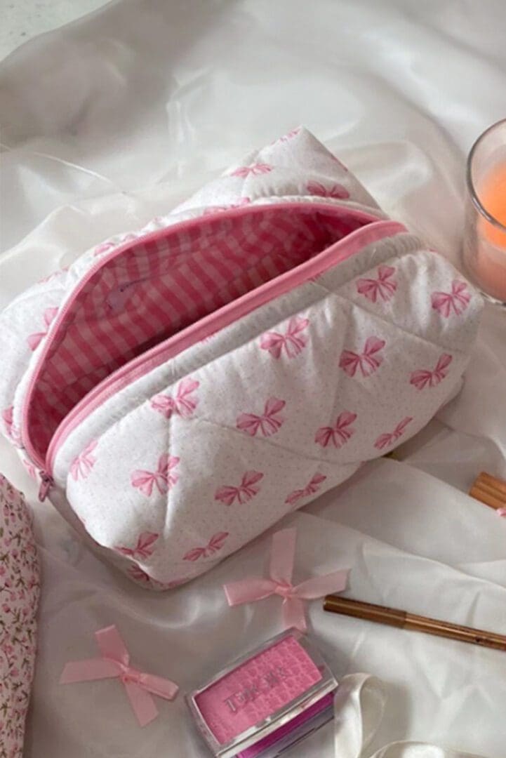 A pink and white quilted bag sitting on top of a table.