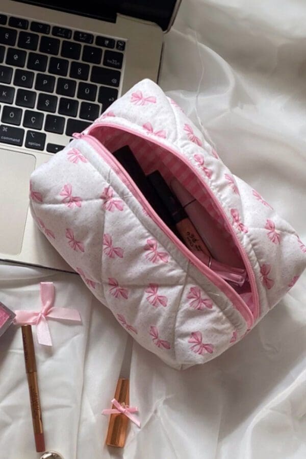 A pink and white quilted bag sitting on top of a bed.