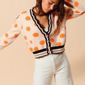 A woman in white pants and orange polka dot sweater.