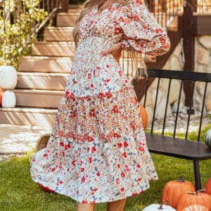 A woman standing in front of pumpkins on the ground.