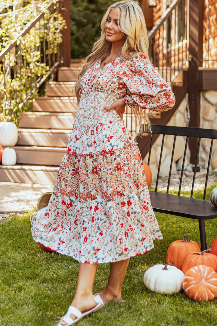 A woman standing in front of pumpkins on the ground.