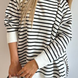 A woman in black and white striped shirt holding a cell phone.