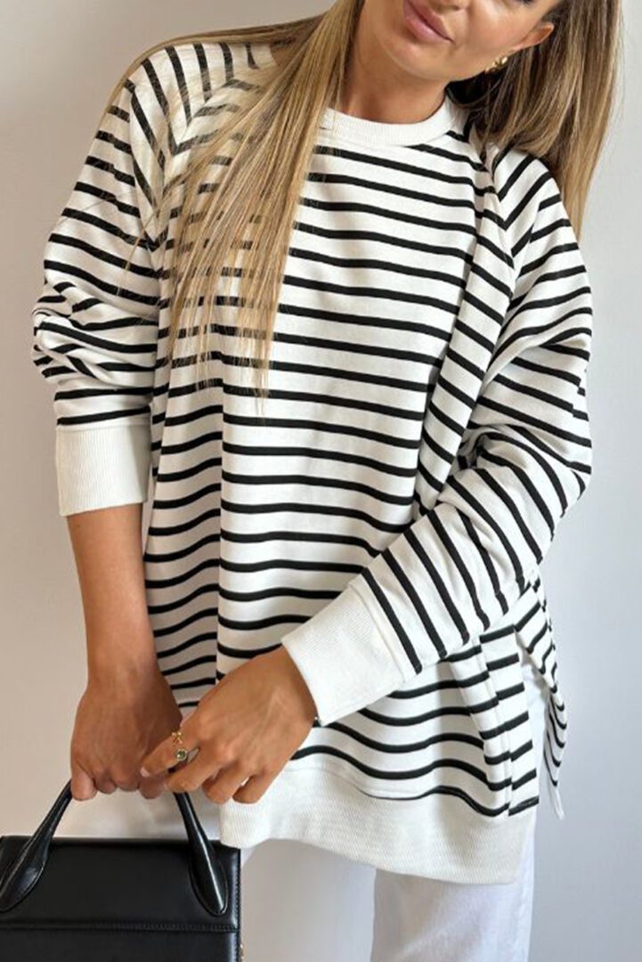 A woman in black and white striped shirt holding a cell phone.