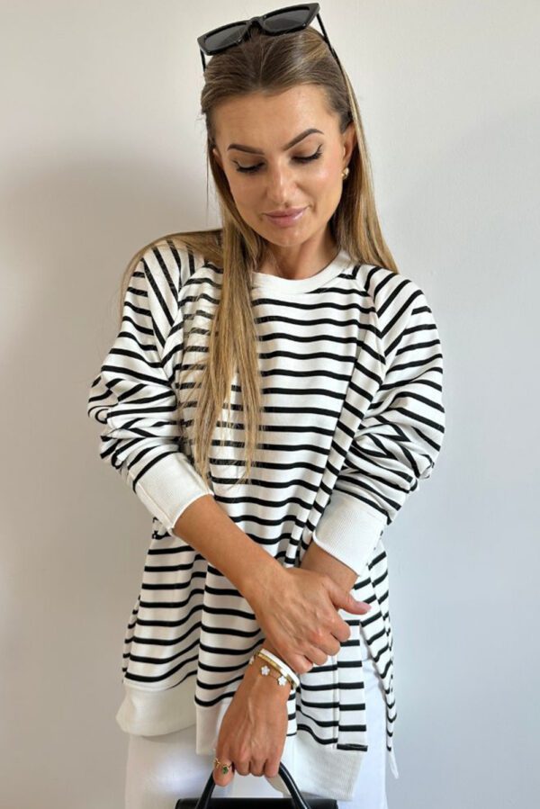 A woman in black and white striped shirt holding a knife.