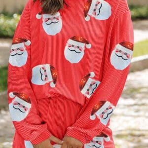 A woman in red santa clause pajamas standing on the street.