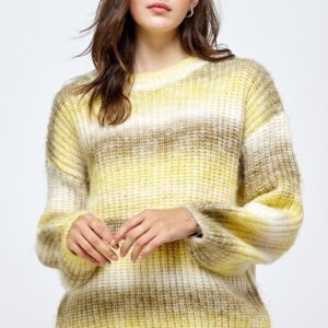 A woman wearing a yellow sweater standing in front of a white wall.