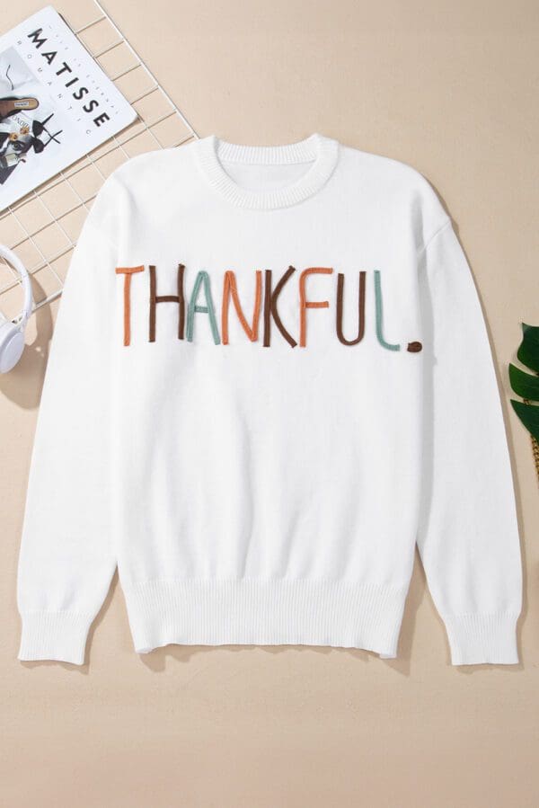 White sweater with Thankful embroidery.