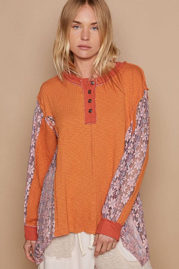 Orange henley top with lace sleeves.